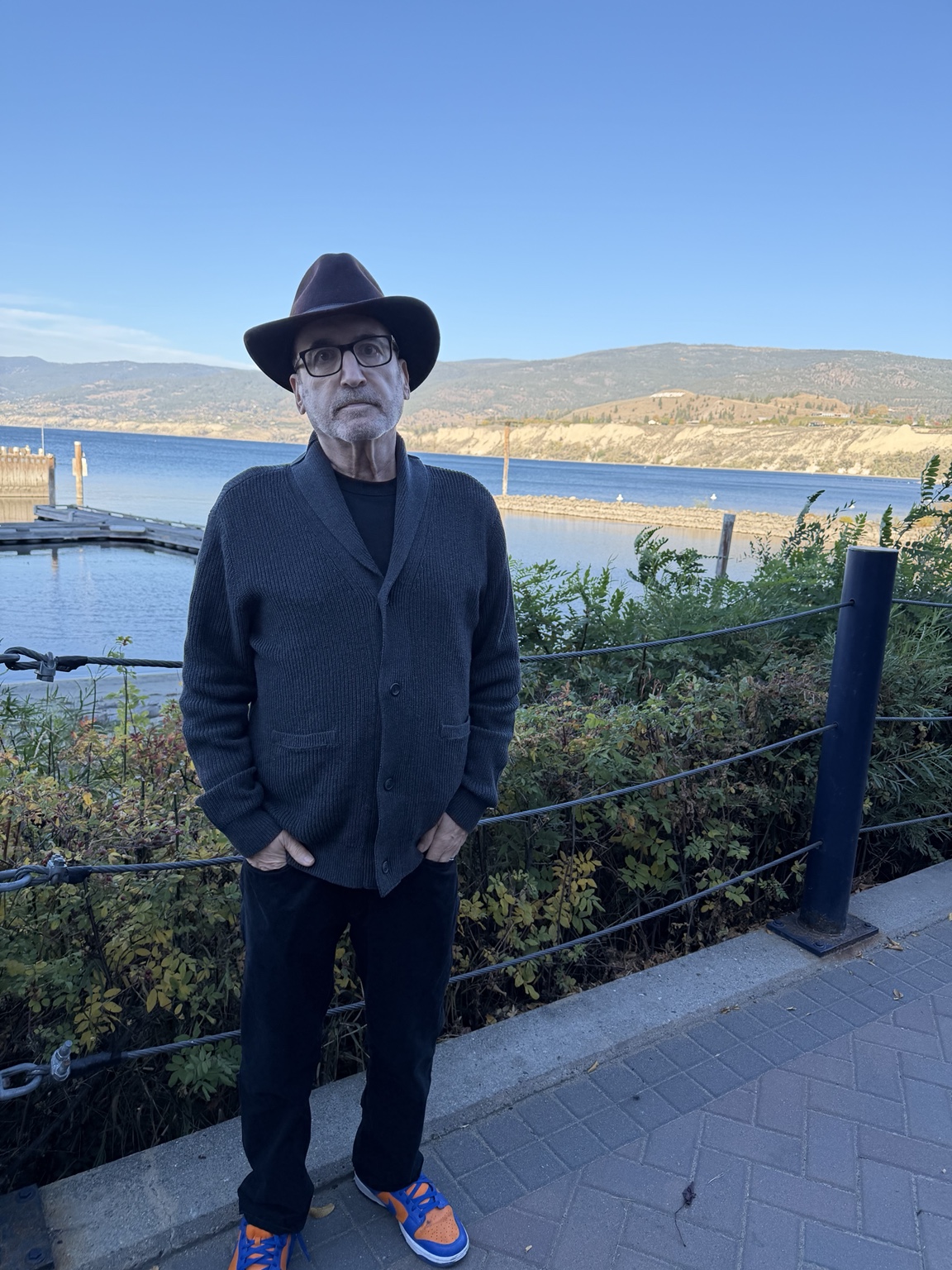 Sheli Teitelbaum in a dark hat and cardigan beside Okanagan Lake in Penticton.